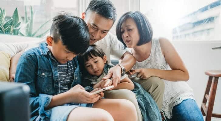 _2020_03_family-using-a-mobile-phone-together-sitting-on-the-sofa-at-home-picture-id1150041859