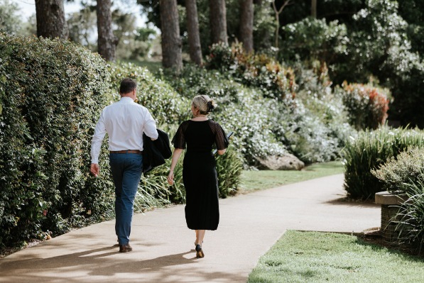 Professional man and woman walking in a garden with backs turned to camera