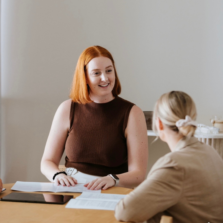 estate-litigation-solicitors Female red-haired estate litigation solicitor smiling at blond female client