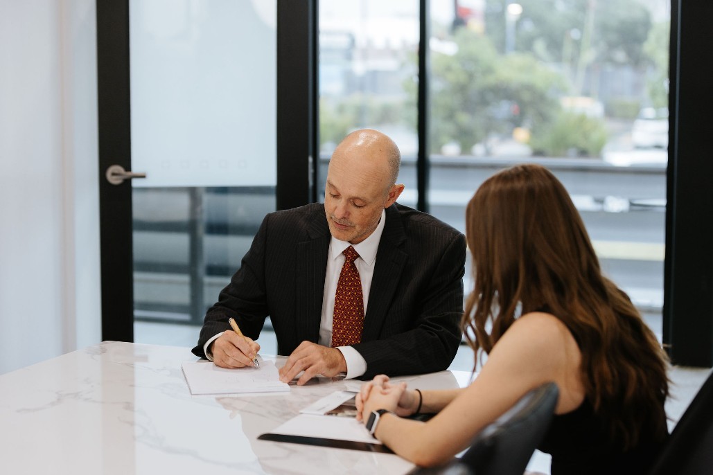 Divorce lawyer speaking with female client and filling out paperwork